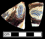 Gray-bodied salt glazed stoneware hollow (mug or jug) with applied  floral motif.  Cobalt-blue and manganese under the glaze. Vessel probably dates to second half of 17th century, based on the applied and incised motifs with cobalt blue and manganese, from 18CV60.