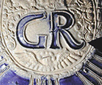 Gray-bodied salt glazed stoneware jug with applied round medallion molded with crowned GR cipher of King George I (1714-1727) or King George II (1727-1760). Just to the right of the angel&rsquo;s wings are the initials SW (see detail).  The initials together on the right hand side in this manner generally indicate a 2 quart jug. Skerry and Hood (2009:50) date these SW marked jugs to the period between 1715 and 1740. Vessel 2317, from 18PR175.
