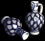 Gray-bodied salt glaze stoneware ovoid jugs  with applied (sprigged) motifs with cobalt blue painted under the glaze.  Cordoned necks and bases and masks on jug necks.Vessel on left, with an applied human face mask is from the outbuilding at Smith's Ordinary and vessel dates c. 1680s. Vessel Number:  ST1-13-2434G/AA; Vessel on right, with applied lion face mask, is from the St. John&rsquo;s Site and also dates to the 1680s.  Vessel Number: 18ST1-23-30.  Vessel has been partially restored.  Vessel heights: 7.75&rdquo; (left) and 8.88&rdquo; (right). Photo courtesy of Historic St. Mary's City, St. Mary's City, MD