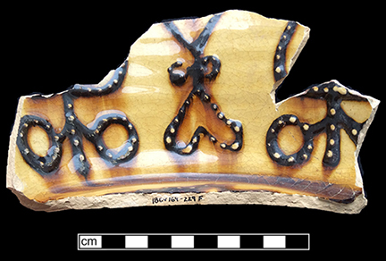 North Midlands slip decorated handled cup.&nbsp;Interior decorated with &ldquo;jeweled&rdquo; dots of slip typical of late 17th- and early 18th-century vessels. Decorated in white and brown slip, Glazed interior (left) and exterior (middle). Base diameter:&nbsp;5.75&rdquo; Lot 229. Paste shot shown on right - from 18CV169. 