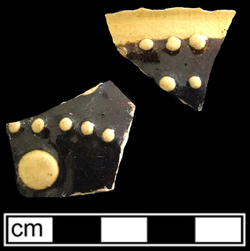 North Midlands slip decorated hollow vessel of indeterminate form.  Exterior decorated with &ldquo;jeweled&rdquo; dots of slip typical of late 17th- and early 18th-century vessels.  Decorated in white and brown slip. Glazed interior and exterior.  Lot 147.