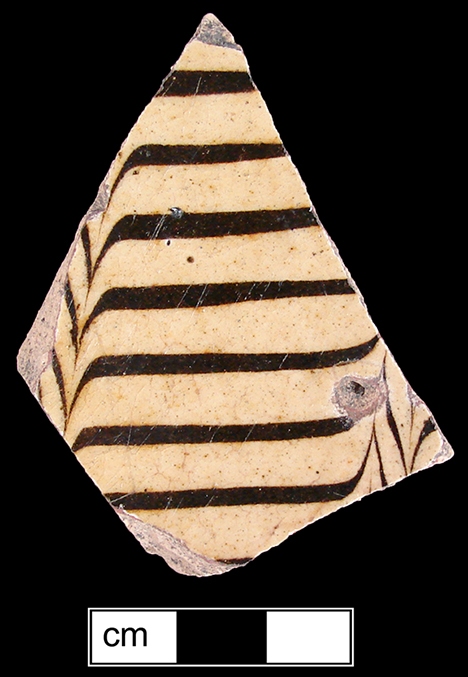 North Midlands combed slipware flat vessel ( most likely a dish). Trailed and combed brown slip on white slip ground. Glazed interior and unglazed exterior - Collected by George L. Miller in 1986 in Staffordshire, England.