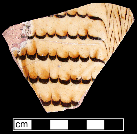 North Midlands combed slipware flat vessel ( most likely a dish). Trailed and combed brown slip on white slip ground. Glazed interior and unglazed exterior - Collected by George L. Miller in 1986 in Staffordshire, England.