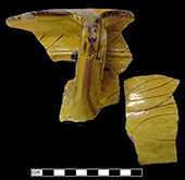 North Devon sgraffito chamberpot  with incised indeterminate motif along rim and body.  White slip over red earthenware body, with lead glazed exterior - QV74.