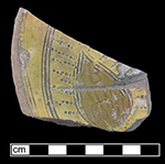 North Devon sgraffito dish with incised probably floral motif. White slip over red and grey earthenware body, with lead glazed interior-QV86.