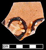 North Midlands slip decorated flat vessel of indeterminate form (probably dish or plate). Decorated in circle and x-pattern in white and brown slip.  Glazed interior, unglazed exterior - Collected by George L. Miller in 1986 in Staffordshire, England.