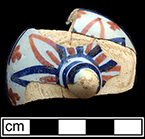 Tin glazed earthenware teapot lid painted in floral motif in red and blue. Rim diameter:  2.00”; Lid height:  1.25” - from 18QU124.