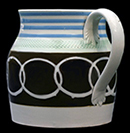 Pearlware jug with overlapping offset circles on black slip. Blue banding along rim and green glazed rouletted band. This jug shape is known as "ship" or "churn", c. 1830,  4.5 inches in height - from a private collection.