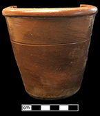 Grey bodied salt glaze stoneware milk pan/bowl. This pan form, with a flat base and sloping sides, was the “universal form of bowl until after about 1860” (Greer 1981:97). The exterior and interior of this vessel was coated with an iron oxide wash or brown clay slip. This vessel has been repurposed as a flower pot by having a hole punched through its base. Rim diameter: 4.58”, Base diameter: 3.00”, Vessel height: 4.50”. Vessel # 57. 18BC56
