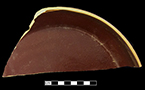North American buff bodied stoneware molded pie pan.  Unglazed exterior, Albany slipped interior. Made in a jigger mold. Base of vessel has impressed/molded lettering that reads “Discoloration or Soaking of Crust”, Rim diameter:  10.00”, Vessel height:  1.50”, from 18CV13.