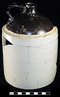 North American buff bodied stoneware jug with Albany slipped shoulder, neck and handle. Bristol glaze covers the cylindrical body. One gallon capacity. Vessel height: 8.00”, Vessel base diameter: 6.00”, Vessel V-15 from 18MO609.