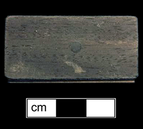 Wooden domino. Two types of wood riveted together from 18BC27, Feature 28. The game of dominoes  originated in China and made its way to Italy in the early 18th century. Game pieces were often made of ivory and ebony (The Strong).  