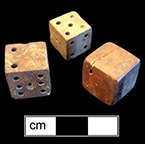 Unfinished bone die.  This example is one of seven unfinished dice or game pieces recovered from this privy.  The die has been shaped and markings made for the placement of the dots, for later drilling.  Each of the pieces has split or shows damage that led to its being discarded before completion. 18BC80