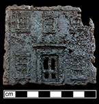 The front of a cast iron toy bank. 8cm x 8cm. See example on right from private collection. The top and bottom parts were screwed into place (N/A 2017). Height: 5.75”, from 18BC27.